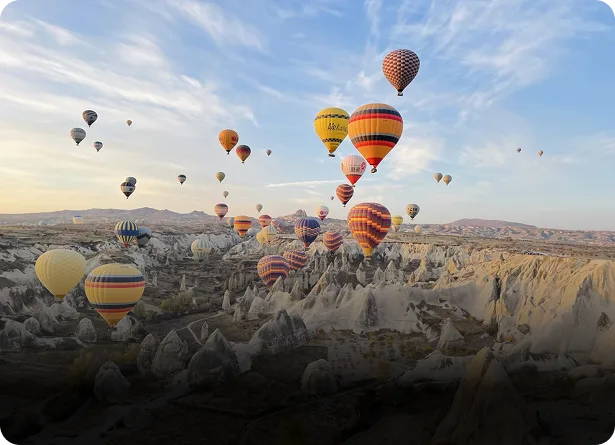 Dozens of colorful hot air balloons floating over the fairy chimneys and rock formations of Cappadocia Turkey at sunrise