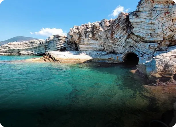 Crystal clear turquoise water beside layered white limestone sea caves on the Izmir coastline Turkey